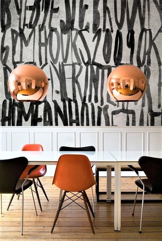 tavolo con sedie colorate e parete con scritte